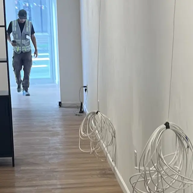 Technician running low-voltage cabling in a commercial hallway