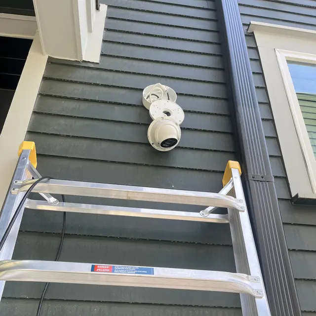 Camera installed on siding beside a ladder